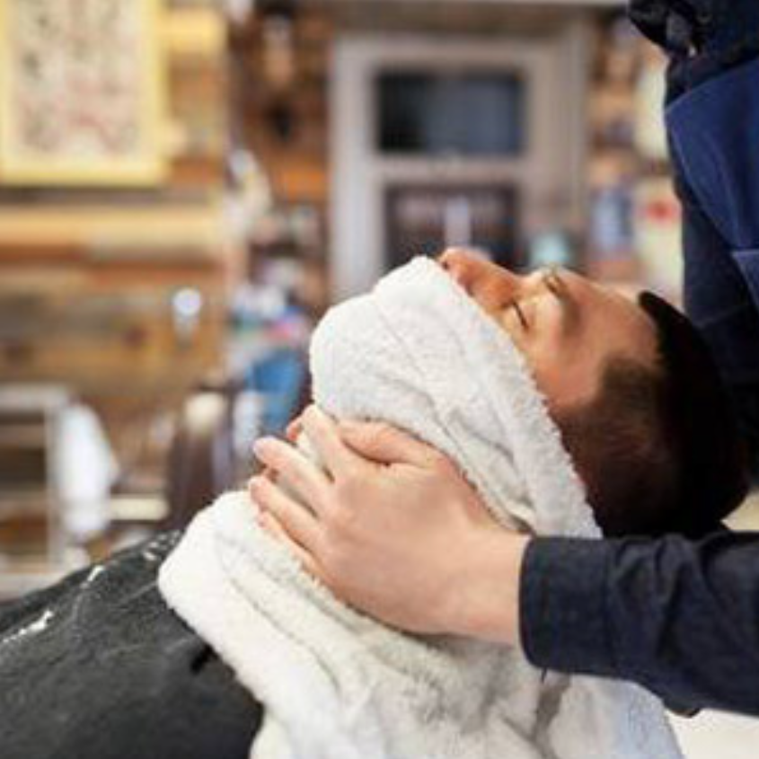 man in barbers chair getting hot towel