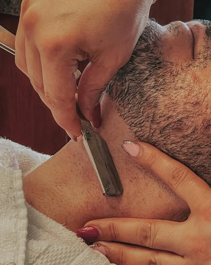 man getting shave in barbershop with straight razor